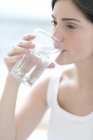 Junge Frau trinkt Glas sauberes Wasser. — Stockfoto