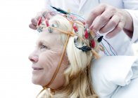 Doctor adjusting electroencephalography equipment on mature patient. — Stock Photo