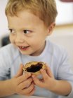 Cheerful boy holding jam tart. — Stock Photo