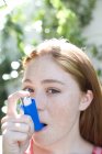 Retrato de menina ruiva adolescente usando o inalador para tratar o ataque de asma . — Fotografia de Stock