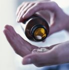 Mãos masculinas derramando pílulas analgésicas de garrafa . — Fotografia de Stock