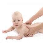 Female hands making baby massage. — Stock Photo