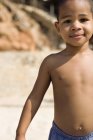Garçon d'âge préscolaire debout à la plage . — Photo de stock