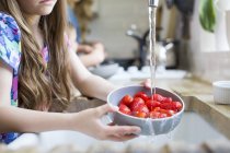 Девушка моет свежую клубнику в раковине . — стоковое фото
