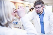 Optometrist trying glasses on woman in shop. — Stock Photo