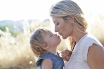 Mother kissing toddler daughter outdoors. — Stock Photo