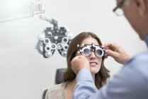 Doctor vistiendo gafas de prueba de la vista de la mujer . - foto de stock