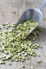 Green split peas on wooden table with scoop. — Stock Photo