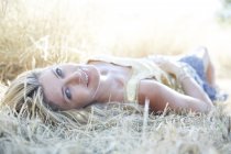 Середня доросла жінка лежить на траві і посміхається . — стокове фото