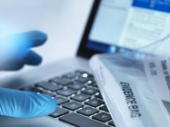 Forensic evidence lying down on laptop with reaching hand, close-up. — Stock Photo