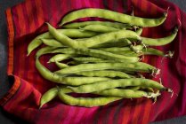 Broad beans on red cloth. — Stock Photo