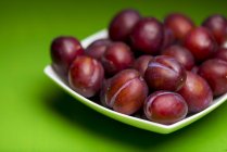 Close-up view of plums on plate, still life. — Stock Photo