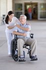 Homem idoso em cadeira de rodas com profissional de saúde . — Fotografia de Stock