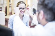 Optométriste essayer des lunettes sur la femme dans le magasin . — Photo de stock