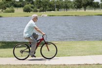 Älterer Mann fährt Fahrrad im Park, Seitenansicht. — Stockfoto