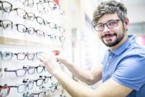 Man at glasses rack in optometrist shop. — Stock Photo