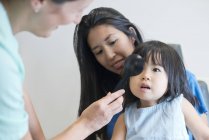 Asian girl with mother having eye test in clinic. — Stock Photo