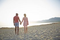 Casal segurando as mãos enquanto caminhava na praia. — Fotografia de Stock