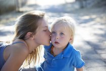 Elementary age girl kissing toddler brother on cheek. — Stock Photo