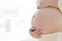 Femme enceinte avec les mains sur le ventre — Photo de stock