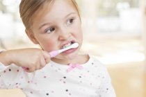 Età elementare ragazza lavarsi i denti e distogliere lo sguardo . — Foto stock