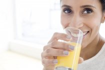 Donna adulta che beve bicchiere di succo d'arancia, ritratto . — Foto stock