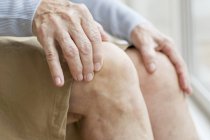 Старша жінка торкається колін, крупним планом . — стокове фото
