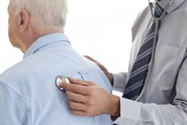 Male doctor examining senior patient, rear view. — Stock Photo