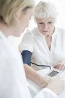 Ärztin nimmt Blutdruck von Seniorin. — Stockfoto
