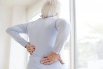 Seniorin reibt sich schmerzenden Rücken, Rückansicht. — Stockfoto