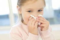 Elementary age girl wiping nose in tissue. — Stock Photo
