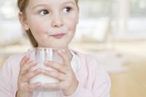 Età elementare ragazza bere bicchiere di latte . — Foto stock