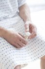 Male patient wearing hospital gown and sitting on bed with urine sample. — Stock Photo