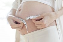 Беременная женщина измеряет живот — стоковое фото