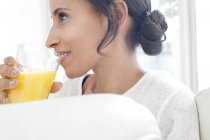 Femme adulte moyenne buvant un verre de jus d'orange, profil . — Photo de stock