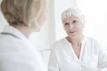 Donna anziana ascoltando medico femminile . — Foto stock
