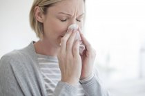 Metà donna adulta soffiando naso con tessuto
. — Foto stock