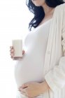Pregnant woman with glass of milk touching tummy. — Stock Photo