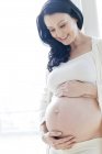 Беременная женщина касается живота и улыбается . — стоковое фото