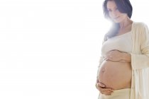 Mujer embarazada tocando la panza sobre fondo blanco . - foto de stock