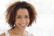 Woman with curly hair smiling at camera — Stock Photo