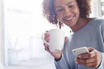 Happy woman with coffee and cell phone — Stock Photo