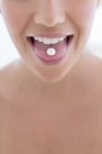 Giovane donna con pillola sulla lingua, primo piano . — Foto stock
