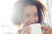 Mujer bebiendo café y mirando hacia otro lado - foto de stock