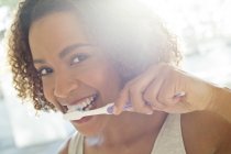 Жінка чистить зуби і дивиться на камеру — стокове фото