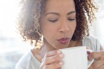 Woman blowing on coffee — Stock Photo