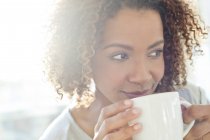Женщина пьет кофе и смотрит в сторону — стоковое фото