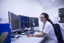 Radióloga que estudia tomografía computarizada en monitores
. - foto de stock