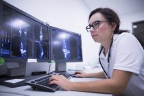 Radiologin untersucht CT-Scans auf Monitoren. — Stockfoto