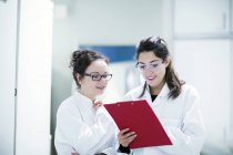 Des scientifiques féminines regardent des notes en laboratoire
. — Photo de stock